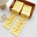 Close-up of yellow sun protection arm sleeves with Doria Dore print on a woven basket - Yellow (10D Dashed Yellow)
