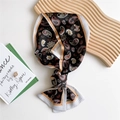 Narrow black paisley print silk scarf tied in a bow on a minimalist desk surface - Black Paisley