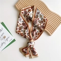 Narrow silk twilly scarf with paisley pattern in beige and orange tied on wood tray - Beige Paisley
