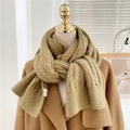 Close-up of mustard yellow cable knit scarf showing thick texture on camel coat - Mustard Green