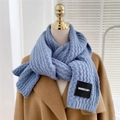 Detail of blue thick knitted scarf with vertical stripe texture and brand woven label - Blue