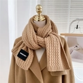 Close-up of camel knit scarf with cable weave texture and brand label detail - Camel