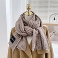 Detail view of thick grey-brown chunky cable knit scarf with a woven brand label - Coffee