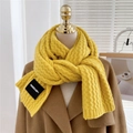 Detail of chunky ginger yellow knit scarf with woven texture and premium brand label - Yellow