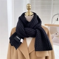 Detail of black thick knitted scarf showing wave texture and woven brand label on camel coat - Black