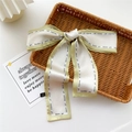 Green and cream silk-like narrow scarf with letter print displayed on a wicker tray - Light Yellow Contrast