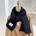 Thick black cable knit scarf on camel coat featuring classic braided texture for winter - Black