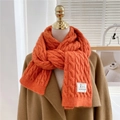 Chunky cable knit orange winter scarf for women styled on a brown wool coat - Orange