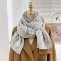 Detail of light gray cable knit winter scarf with a white woven label on camel wool coat - Gray