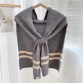 Detail of grey knitted shawl with beige stripes hanging on a wooden hanger - Gray