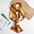 Floral print narrow silk scarf in ginger and caramel tones styled on a wooden display - Orange Floral Frame
