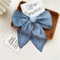Sky blue pleated long scarf with navy trim and artistic lettering in a woven basket - Pleated Blue with Letter Edge