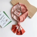 Elegant orange and white geometric silk twilly scarf displayed on a wooden tray - Red Crease Line