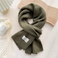 Olive green ribbed knit scarf with branded tag on a cozy minimalist background - Dark Green