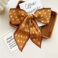 Ginger yellow pleated bow hair accessory with white polka dots on a rattan basket - Pleated Orange Polka Dot