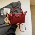 Elegante borsa in pelle bordeaux con ciondolo in peluche su sfondo di tendenza - Rosso Vino con Ciondolo