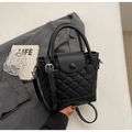 Detail der schwarzen gesteppten Leder-Beuteltasche mit Litschi-Struktur auf grauem Sakko - Schwarz