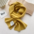 Detail of ginger yellow knitted scarf with handmade label on wavy wooden display - One Size / Yellow