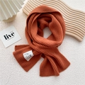 Detail of burnt orange knit scarf featuring ribbed texture and handmade woven label - One Size / Orange Red