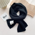 Close-up of black ribbed knit scarf featuring a white hand made brand label and soft texture - One Size / Black