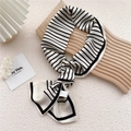Elegant black and white striped silk scarf with a satin finish shown on a wooden display - Striped Long Grid