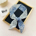 Elegante foulard sottile in seta a fiori blu annodato su espositore decorativo - Blu Mezza Floreale