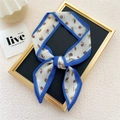Blue and white skinny scarf with hand-drawn fruit pattern tied in a bow on a display stand - Tomato Blue