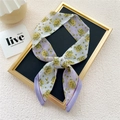 Elegant narrow lavender floral silk twilly scarf tied in a bow on a display board - Yellow Plum Purple