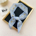 Light blue narrow silk scarf with white daisy print tied in a bow on display - Blue Double-Sided Daisy