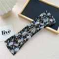 Detail view of the floral fabric pattern and center slot of this lazy hair curler tool - Blue Green Leaf Black