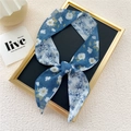 Narrow blue floral patterned silk scarf tied as a bow on a decorative frame - Light Blue White Magnolia