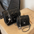 Black quilted chain shoulder bags in two sizes on stone display with metallic accents - Large / Black