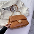 Brown quilted chain shoulder bag with gold metal clasp on elegant white tweed background - Brown
