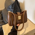 Elegante braune Lederhandtasche mit Zebramuster und Goldschnalle auf Steinsockel - Braun