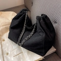 Schwarze Denim-Cloud-Tasche mit Silberkette auf einem cremefarbenen Blazer - Schwarz