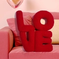 Detalle de cojines decorativos LOVE de forro polar rojo en un sofá de salón rosa - Cojín LOVE / Rojo