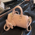 Pink lychee grain leather cylinder bag with bow charm and golden metal hardware - Pink