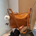 Brown vintage faux leather bucket bag with plush charm and embossed logo detail - Brown