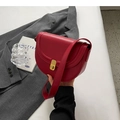 Red leather saddle bag with gold metal buckle shown in a lifestyle fashion setting - Burgundy