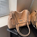 Apricot tote bag with silver chain strap and metal logo plate shown in elegant setting - Khaki