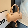 Borsa a mano cilindrica beige con trama a pieghe e dettagli in argento tenuta in mano - Cachi