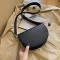 Black saddle bag featuring contrast textures with adjustable strap on a wood background - Black