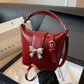 Borsa a secchiello in pelle lucida rosso scuro con fiocco argento e tracolla regolabile - Rosso