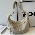 Beige nylon hobo bag with adjustable strap and woven zipper pull in a minimalist setting - Off White