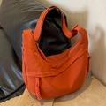 Orange nylon crescent crossbody bag with textured fabric and woven rope pendant - Orange