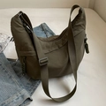 Olive green nylon crescent shoulder bag with adjustable strap on white fabric background - Green