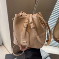 Bolso tipo cubo tejido beige con retales de cuero y correa ajustable en habitación - Caqui