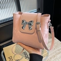 Pink bucket handbag with silver bow detail and adjustable shoulder strap on marble - Pink
