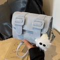 Hellblaue Umhängetasche aus Leder mit einem weißen Plüschmonster-Anhänger als Detail - Blau mit Anhänger