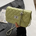 Quilted avocado green chain crossbody bag with silver twist lock on dark grey suit - Green